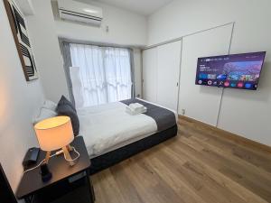 a bedroom with a bed and a flat screen tv at OUCHI HOTEL Peace Memorial Park in Hiroshima