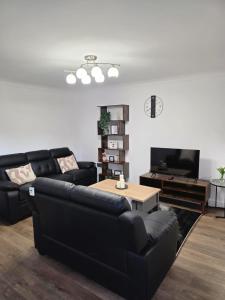 a living room with a black couch and a table at Charming three bedroom house in Durham in Brandon