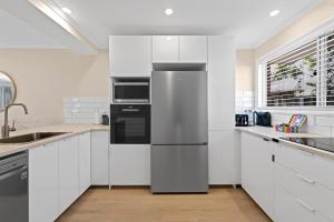 a kitchen with white cabinets and a stainless steel refrigerator at Family Friendly 2 Bed Flat with Balcony in Mooloolaba
