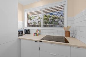 a white kitchen with a sink and a window at Family Friendly 2 Bed Flat with Balcony in Mooloolaba