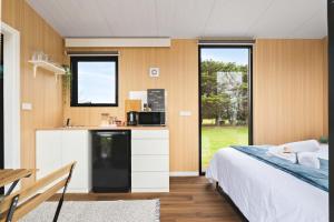 a bedroom with a bed and a kitchen with a microwave at Oceans Edge Retreat by Tiny Away in Portland