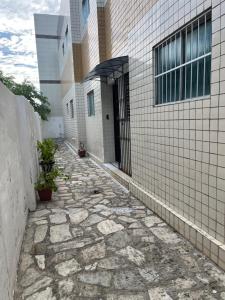 a stone walkway leading to a building with a door at Apartamento simples e Familiar conforto e sossego in João Pessoa