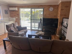 a living room with a couch and a television at Beachlander Self-Contained Holiday Apartments in Coffs Harbour