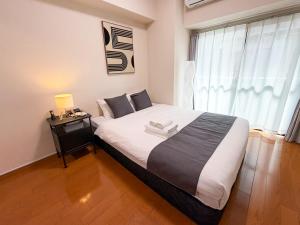 a bedroom with a bed with a night stand and a window at OUCHI HOTEL Peace Memorial Park in Hiroshima