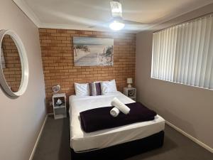 a bedroom with a bed and a brick wall at Beachlander Self-Contained Holiday Apartments in Coffs Harbour +79 photos