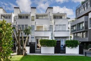 a large white building with bushes in front of it at QV Stays Modern Spacious Multi-Level Townhouse in Auckland