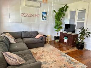 a living room with a couch and a tv at Peach Me Beach Shack in Boat Harbour