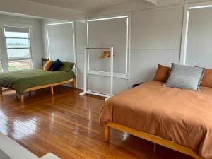 a bedroom with a bed and a bench in it at Peach Me Beach Shack in Boat Harbour