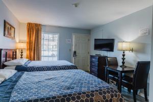 a hotel room with two beds and a desk and a television at Jackson Town House Inn in Jackson