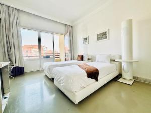 a white bedroom with two beds and a large window at La Renaissance hôtel Marrakech in Marrakesh +74 photos