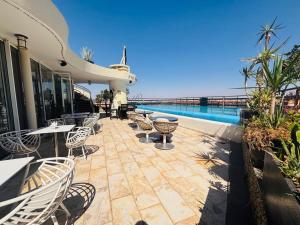 a patio with tables and chairs next to a pool at La Renaissance hôtel Marrakech in Marrakesh