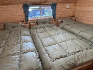 a group of three beds in a room at Villa Aso Otohime in Uchinomaki