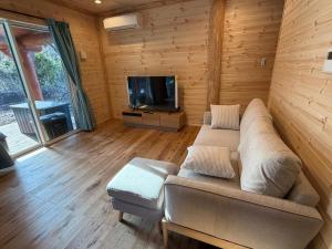 a living room with a couch and a flat screen tv at Villa Aso Otohime in Uchinomaki