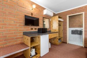 a room with a tv and a brick wall at Edithburgh Seaside Motel in Edithburgh