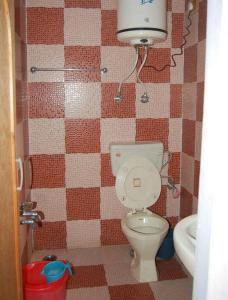 a bathroom with a toilet and a tiled wall at Hotel First Kashmir in Srinagar +12 photos