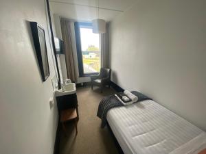 a hotel room with a bed and a chair and a window at The Old Railway Hotel Lumsden in Lumsden
