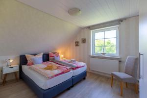 a bedroom with a bed and a window and a chair at Hus-Pellworm-2-Ferienwohnung-Meereswelle in Pellworm