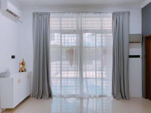 a large window with gray curtains in a room at Homestay Sri Aman in Simanggang +1 photo