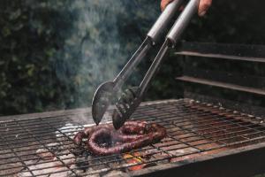 a steak being grilled on a grill with a spatula at The Little Thatch Cottage in Greyton