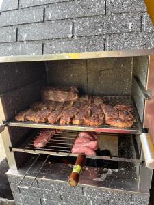 a grill with meat and other food on it at Casa Espaçosa com Piscina, 4 Quartos e Ar-Condicionado in Itanhaém