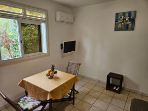 a dining room with a table and a television at Orchidée in Capesterre-Belle-Eau