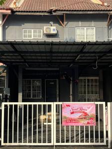 a sign on a fence in front of a house at Sweet Roses Homestay- Free WiFi, Nearby UiTM in Bandar Puncak Alam