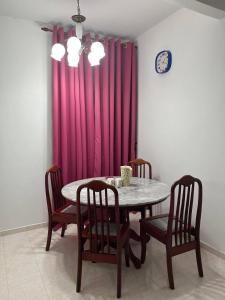a dining room table with chairs and a pink curtain at Sweet Roses Homestay- Free WiFi, Nearby UiTM in Bandar Puncak Alam