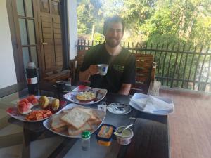 a man sitting at a table with two plates of food at Ella Field Side View Rooms & Cafe in Demodera