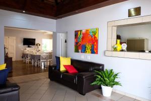 a living room with a black leather couch with colorful pillows at Firwood Lodge in Pretoria