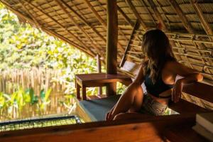 a woman sitting on a bench in a hut at Bamboo Jungle Villa's in El Nido