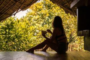 a woman sitting on a table with a book at Bamboo Jungle Villa's in El Nido