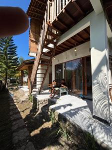 a man sitting on a bench outside of a house at THE NYAMO surfschool & stay in Pulukan