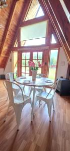 a white table with chairs and a vase with flowers at Cabaña Alpina 2 in Coñaripe
