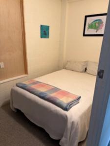 a small bedroom with a bed with a blanket on it at Hosts on the Coast Ocean Corner in Whangamata