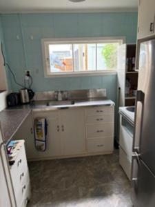 a small kitchen with a sink and a window at Hosts on the Coast Ocean Corner in Whangamata +3 photos
