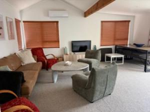a living room with a couch and a table and a piano at Hosts on the Coast Ocean Corner in Whangamata