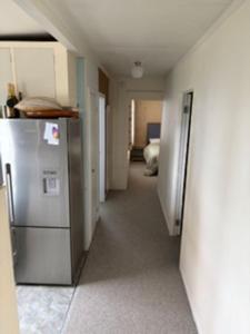an empty hallway with a refrigerator in a room at Hosts on the Coast Ocean Corner in Whangamata