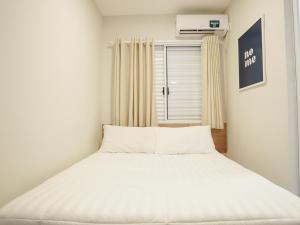 a white bed in a room with a window at Apê Brooklin -Berrini in São Paulo