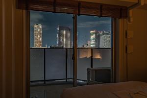 a bedroom with a view of a city skyline from a window at ESLEAD HOTEL Namba East in Osaka