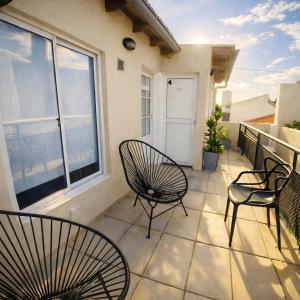a balcony with three chairs and a window at Gotas de Rocío - para 4 en San Antonio Oeste in San Antonio Oeste