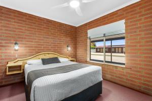 a brick walled bedroom with a bed and a window at Edithburgh Seaside Motel in Edithburgh
