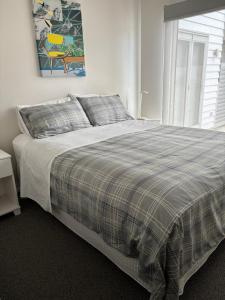 a bed with a plaid blanket and pillows in a bedroom at Aquila Nest in Whitianga