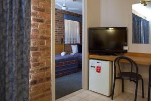a living room with a television and a room with a chair at Paddlewheel Motel in Echuca