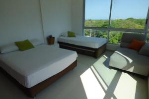 a bedroom with two beds and a couch and a window at Costa Azul Suites 401 in Santa Marta +89 photos