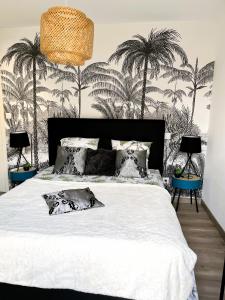a bedroom with a white bed with palm trees on the wall at Villa l'Immortelle in Zonza +33 photos