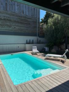 a swimming pool with a chair on a wooden deck at Villa l'Immortelle in Zonza