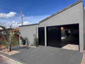 a gray building with a garage with a black door at Casa de lazer privativa in Barretos