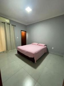 a bedroom with a bed with pink sheets on it at Casa de lazer privativa in Barretos