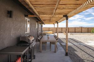 a patio with a wooden pergola and a table at Dark Star - Endless Stars, Cowboy Pool, Spa, Fire pit, BBQ in Twentynine Palms