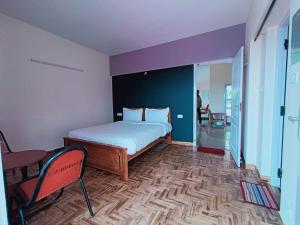 a bedroom with a bed and a table and a chair at Ooty Peak view villa in Ooty
